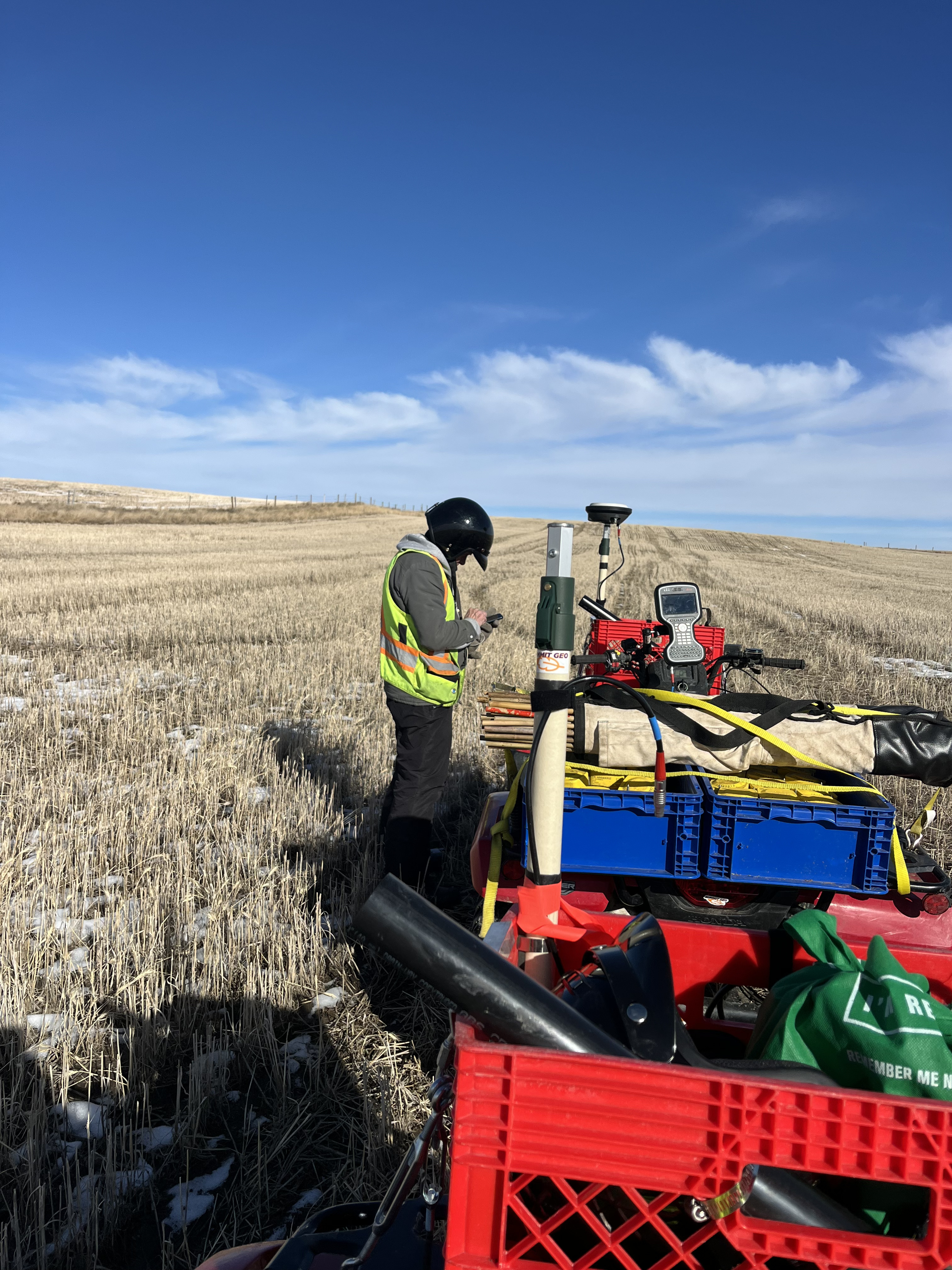 Surveyor with quad and GNSS gear in stubble field