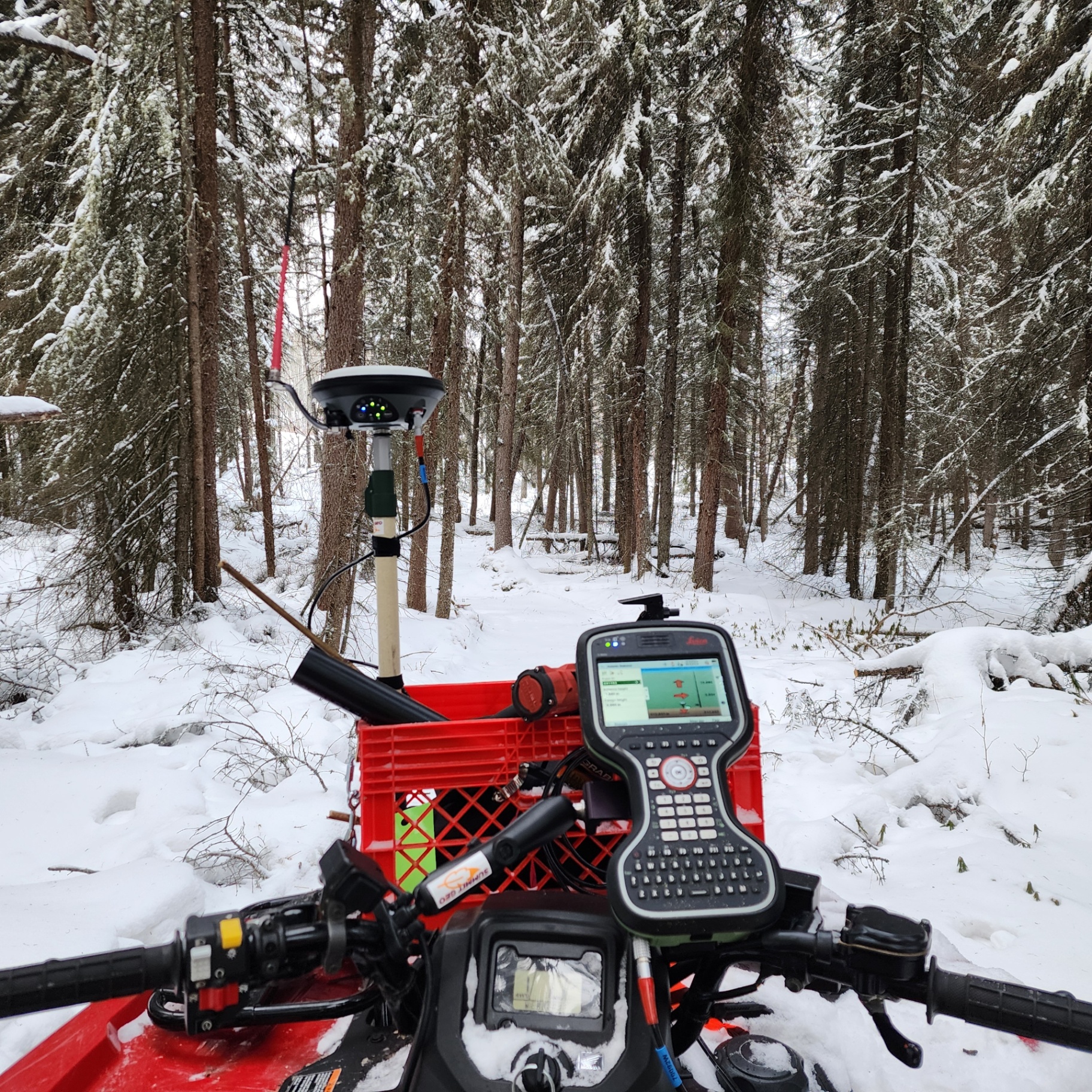 GNSS rover and Leica controller mounted on a quad in a snowy forest