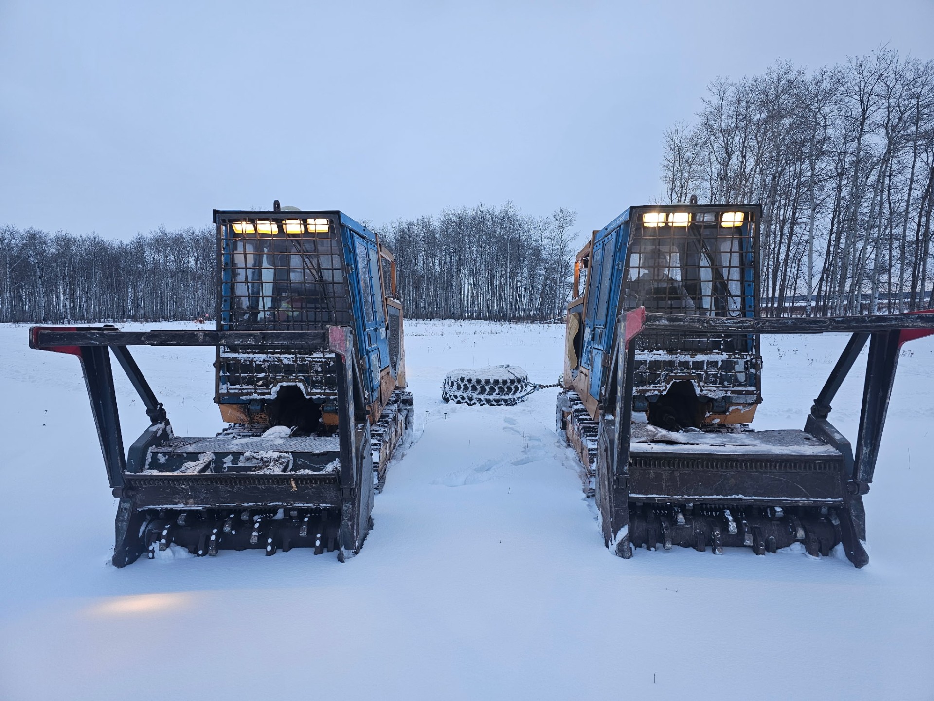 Two mulchers framed symmetrically in a snowy field