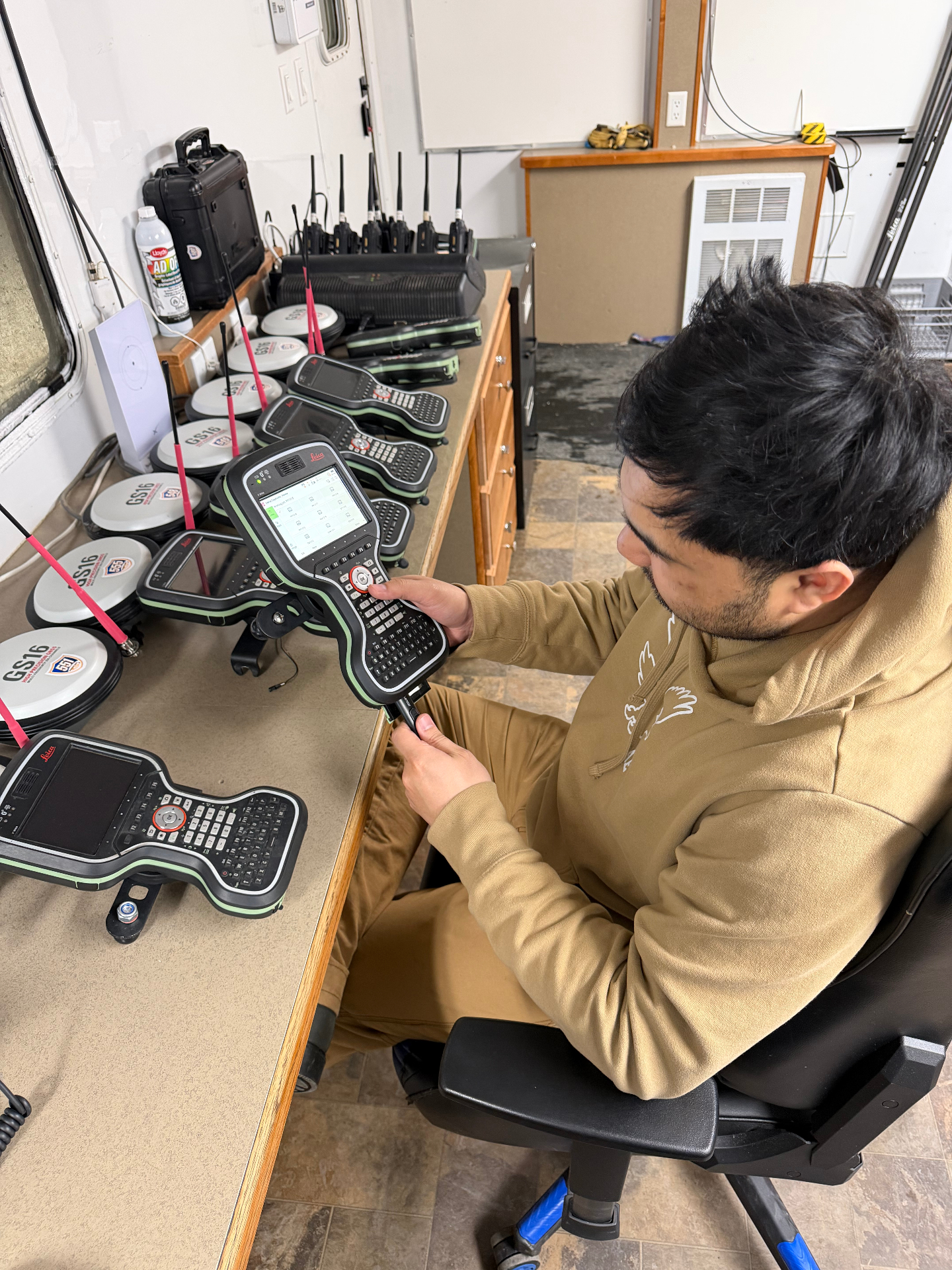 Crew member configuring a Leica GNSS controller in the field office