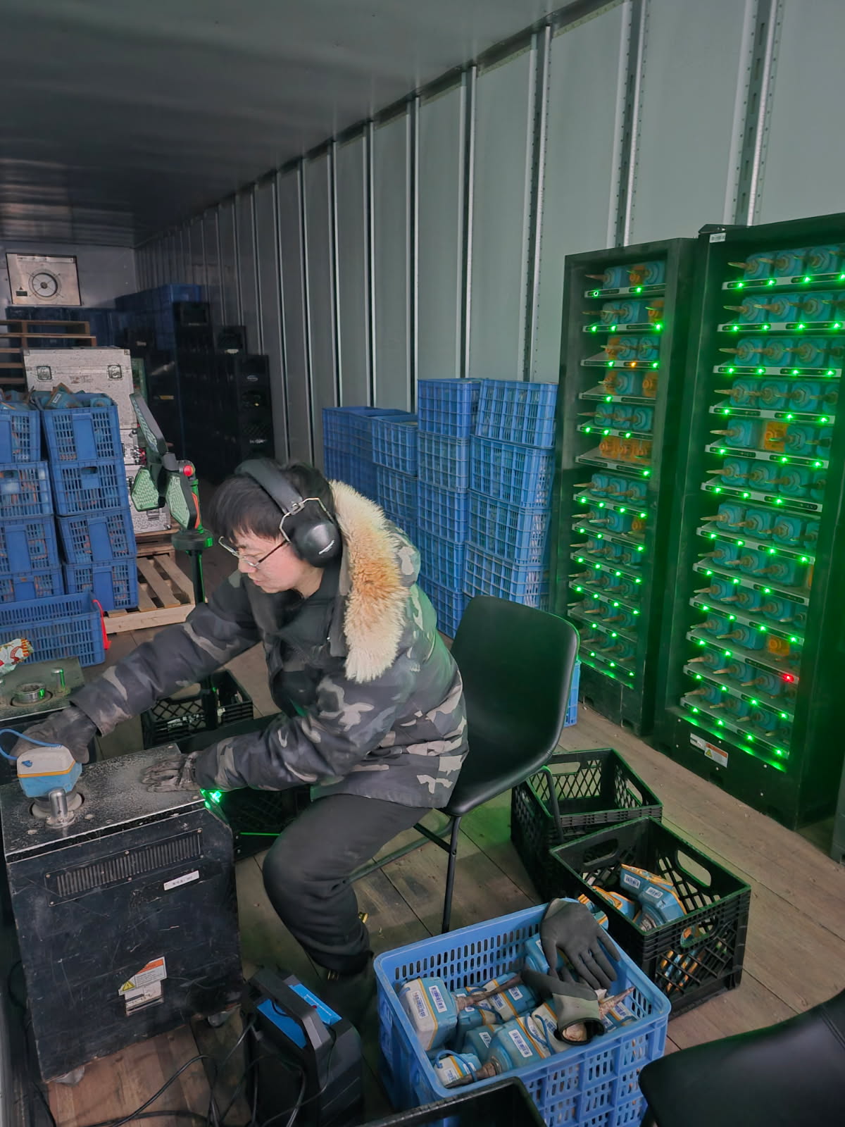 Field technician downloading geophone data from racks of wireless nodes lit with green status LEDs