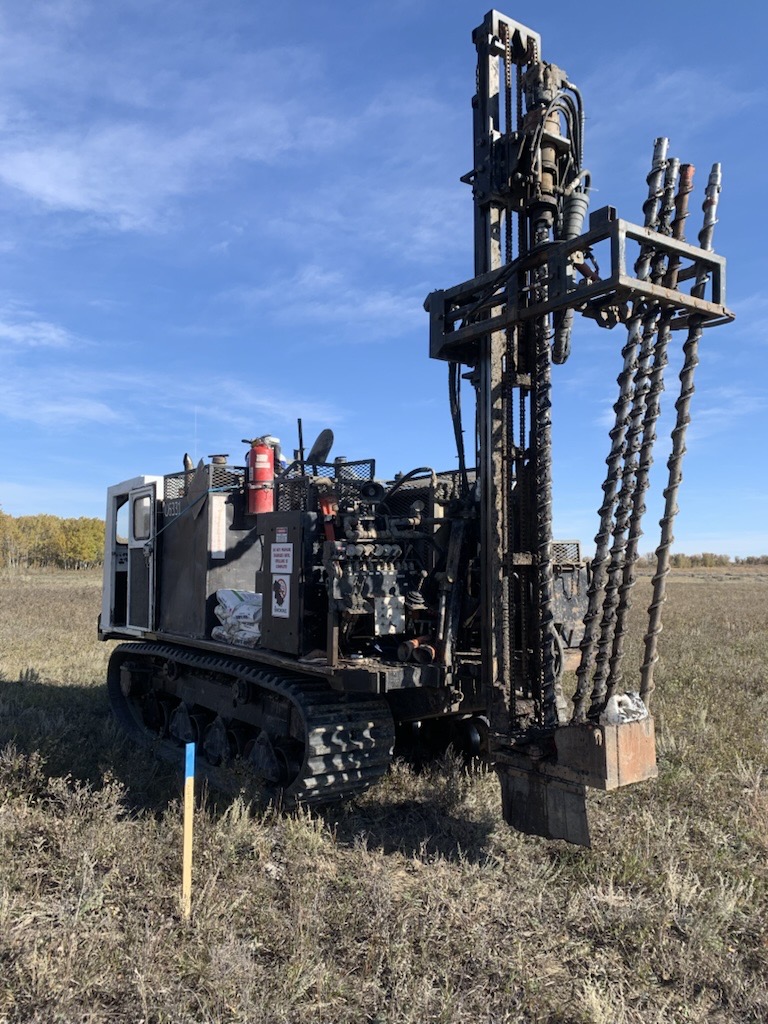 Tracked shot-hole drill rig staged in a prairie field for dynamite-source seismic acquisition
